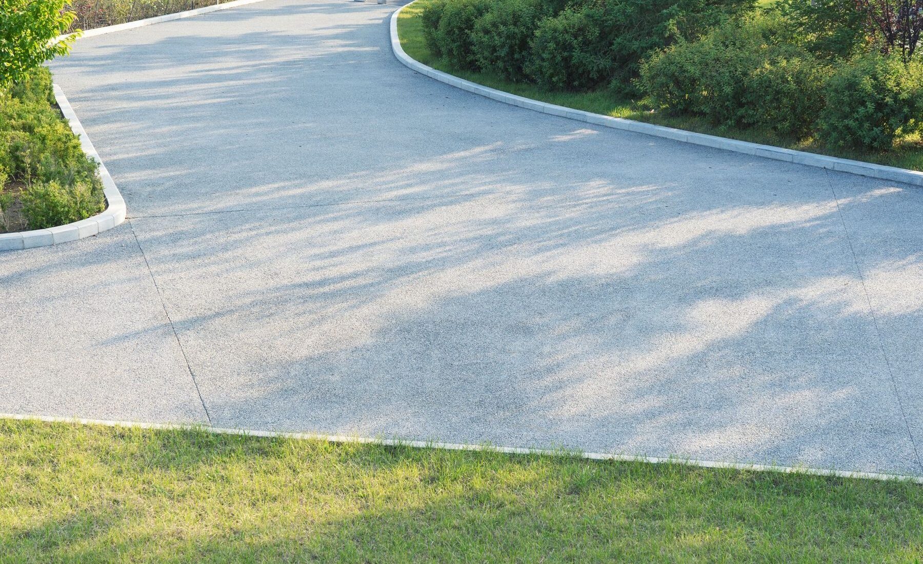 A freshly poured concrete driveway curving toward a home